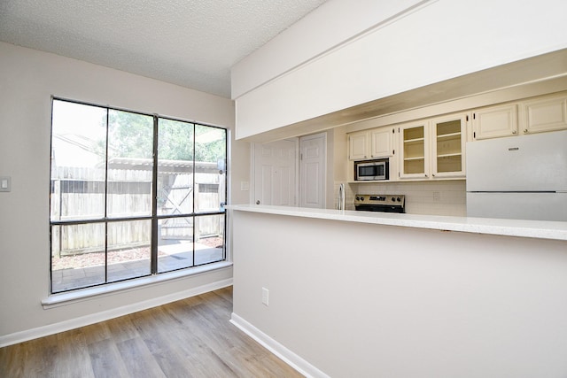 5001 Lamonte Ln Unit 14, Houston, TX 77092 - kitchen featuring stainless steel appliances, light countertops, backsplash, glass insert cabinets, and light wood-style flooring