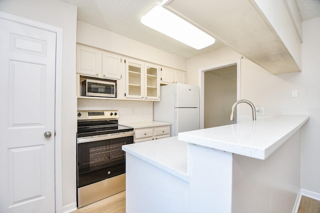 5001 Lamonte Ln Unit 14, Houston, TX 77092 - kitchen featuring stainless steel appliances, a peninsula, glass insert cabinets, decorative backsplash, and light wood finished floors