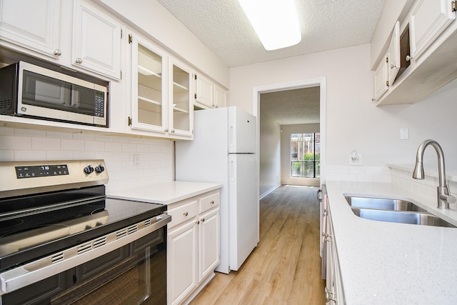 5001 Lamonte Ln Unit 14, Houston, TX 77092 - kitchen featuring appliances with stainless steel finishes, a sink, a textured ceiling, light countertops, and light wood-style floors