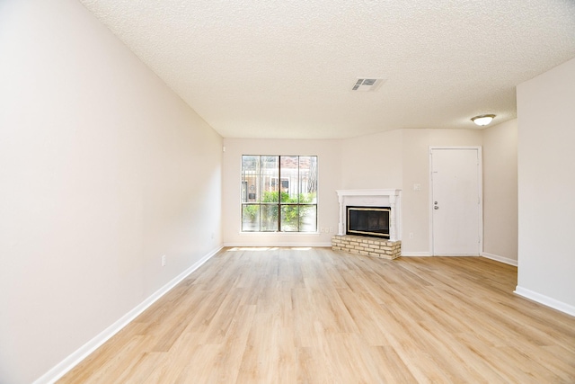 5001 Lamonte Ln Unit 14, Houston, TX 77092 - unfurnished living room with light wood finished floors, baseboards, a textured ceiling, and a brick fireplace