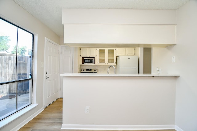 5001 Lamonte Ln Unit 14, Houston, TX 77092 - kitchen with appliances with stainless steel finishes, light wood-style floors, glass insert cabinets, light countertops, and backsplash
