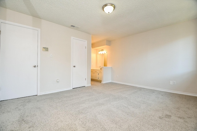 5001 Lamonte Ln Unit 14, Houston, TX 77092 - unfurnished bedroom with light carpet, baseboards, a textured ceiling, and ensuite bathroom