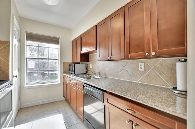9003 Gaylord St Unit 12, Houston, TX 77024 - kitchen featuring appliances with stainless steel finishes, backsplash, brown cabinets, and light tile patterned floors