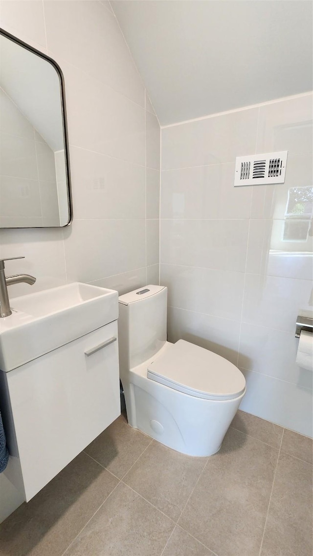 6658 Radley Dr, Spring, TX 77379 - bathroom featuring tile walls, toilet, vanity, tile patterned flooring, and lofted ceiling