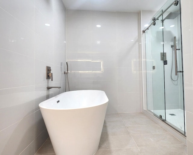 6658 Radley Dr, Spring, TX 77379 - bathroom featuring a shower stall, a freestanding bath, tile walls, and tile patterned floors