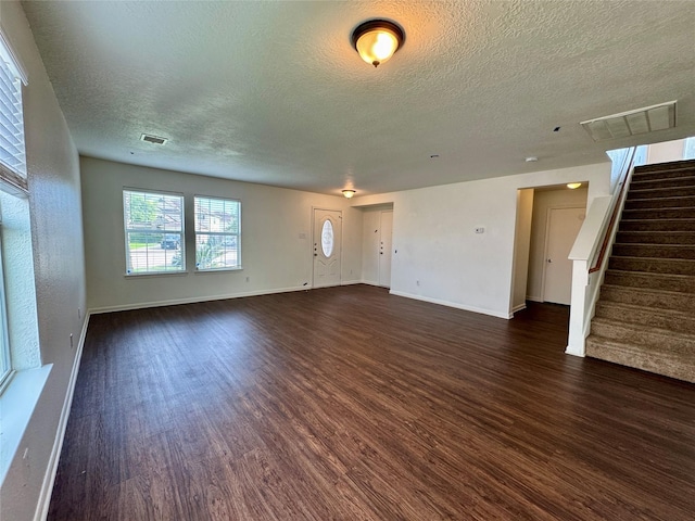 15507 Liberty Bluff Dr, Houston, TX 77049 - unfurnished living room with dark wood-type flooring, a textured ceiling, baseboards, and stairway