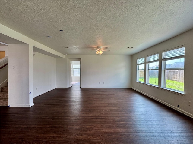 15507 Liberty Bluff Dr, Houston, TX 77049 - empty room featuring dark wood-style flooring, stairs, ceiling fan, a textured ceiling, and healthy amount of natural light