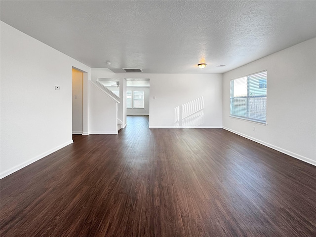 15507 Liberty Bluff Dr, Houston, TX 77049 - unfurnished living room featuring plenty of natural light, dark wood-style flooring, stairway, and a textured ceiling