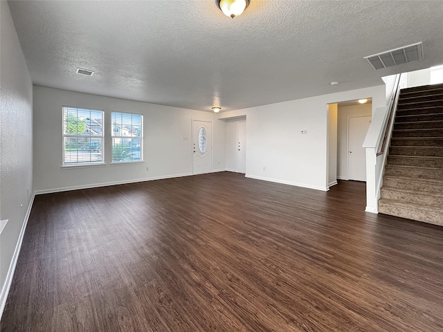 15507 Liberty Bluff Dr, Houston, TX 77049 - unfurnished living room with dark wood-style flooring, a textured ceiling, and stairway