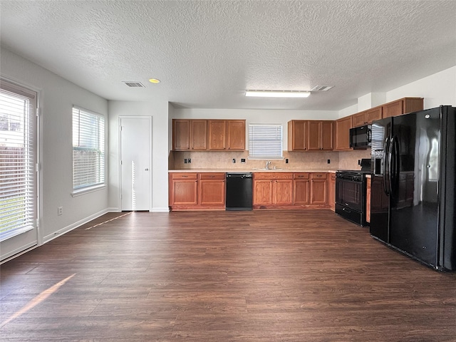 15507 Liberty Bluff Dr, Houston, TX 77049 - kitchen with black appliances, dark wood finished floors, a textured ceiling, light countertops, and brown cabinetry