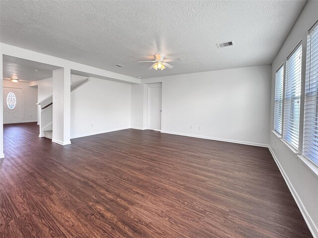 15507 Liberty Bluff Dr, Houston, TX 77049 - spare room with a textured ceiling, dark wood-style flooring, a ceiling fan, and stairs