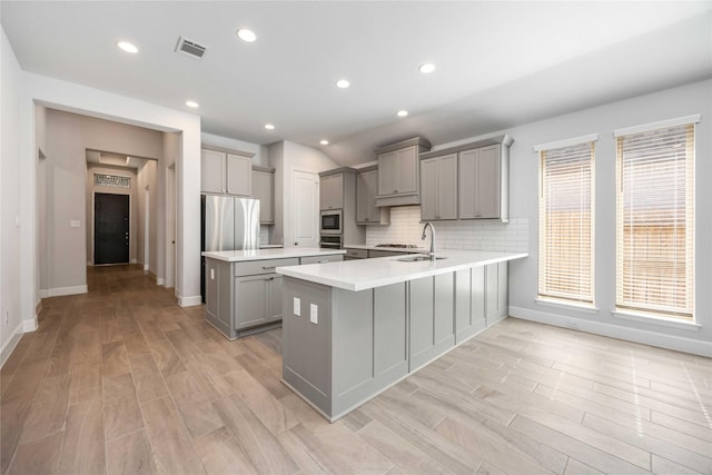 15711 Autumn Sun Ct, Conroe, TX 77302 - kitchen featuring gray cabinets, stainless steel appliances, a peninsula, light countertops, and a sink