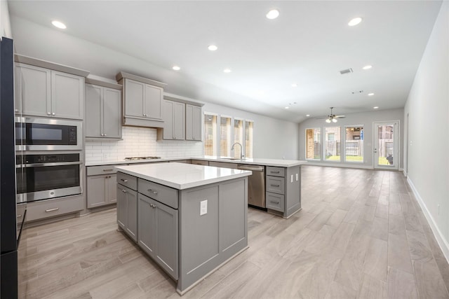 15711 Autumn Sun Ct, Conroe, TX 77302 - kitchen featuring gray cabinetry, appliances with stainless steel finishes, a peninsula, a center island, and recessed lighting
