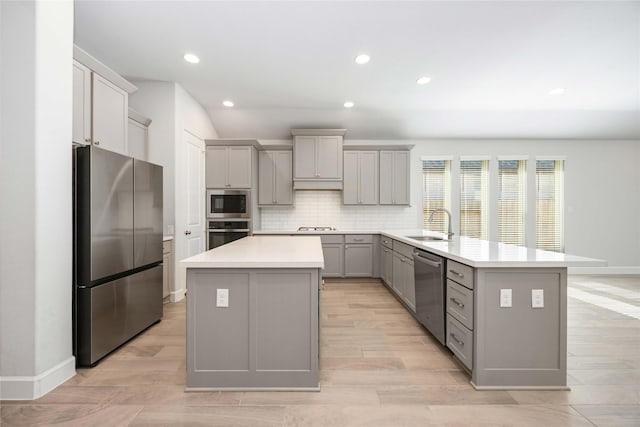 15711 Autumn Sun Ct, Conroe, TX 77302 - kitchen featuring appliances with stainless steel finishes, gray cabinets, a kitchen island, a sink, and a peninsula