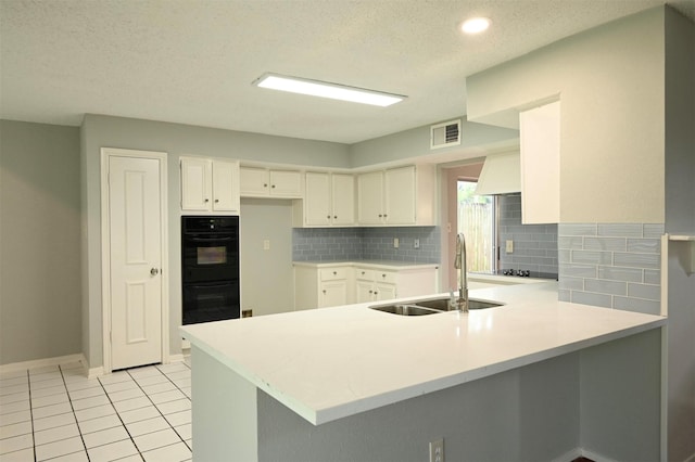 3114 Hollow Creek Ct, Houston, TX 77082 - kitchen featuring a peninsula, a sink, decorative backsplash, white cabinets, and a textured ceiling