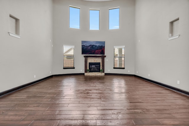 5912 T St, Katy, TX 77493 - unfurnished living room featuring wood-type flooring, a high ceiling, a glass covered fireplace, and baseboards