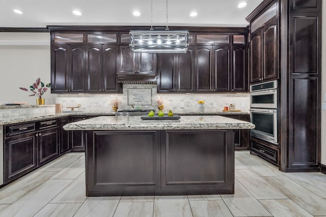 5912 T St, Katy, TX 77493 - kitchen with stainless steel double oven, a kitchen island, decorative backsplash, decorative light fixtures, and light stone countertops