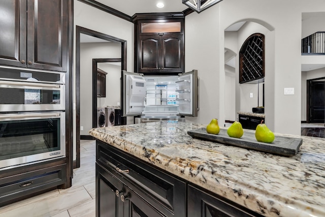 5912 T St, Katy, TX 77493 - kitchen with independent washer and dryer, stainless steel double oven, light stone counters, and dark brown cabinets