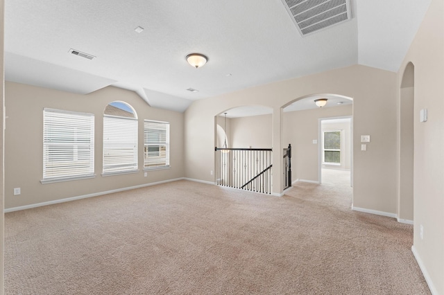 406 Oak Stream Dr, Conroe, TX 77304 - empty room featuring light colored carpet, vaulted ceiling, baseboards, and arched walkways