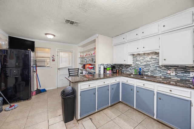 917 Alvin St, Pasadena, TX 77506 - kitchen featuring freestanding refrigerator, a sink, blue cabinets, a peninsula, and light tile patterned flooring