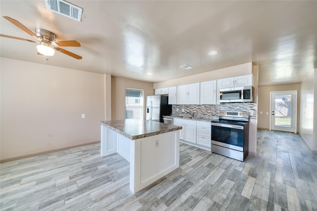 16538 Park Scot Dr, Houston, TX 77084 - kitchen with stainless steel appliances, plenty of natural light, white cabinets, backsplash, and recessed lighting