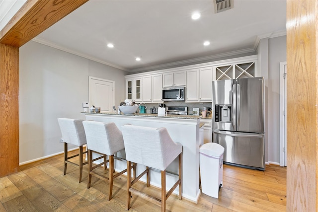 1538 Bevis St, Houston, TX 77008 - kitchen featuring stainless steel appliances, light wood-style flooring, crown molding, glass insert cabinets, and white cabinets