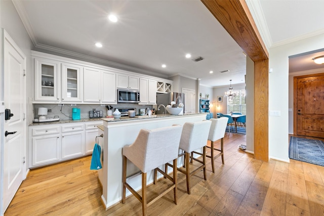 1538 Bevis St, Houston, TX 77008 - kitchen with stainless steel appliances, a breakfast bar, white cabinetry, decorative backsplash, and glass insert cabinets