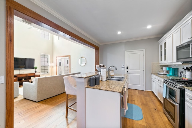1538 Bevis St, Houston, TX 77008 - kitchen featuring a sink, stainless steel appliances, a kitchen bar, light wood-style flooring, and white cabinets