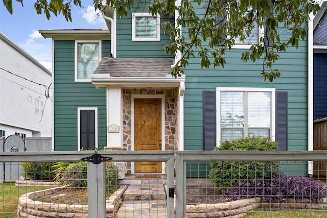 1538 Bevis St, Houston, TX 77008 - view of front of home featuring a fenced front yard, stone siding, a shingled roof, and a gate