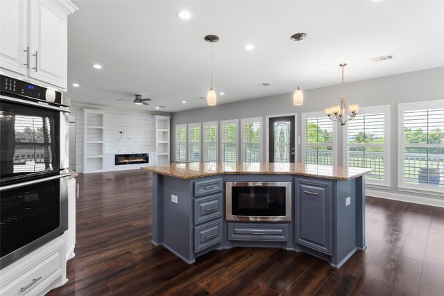 610 S Shady Ln, Shoreacres, TX 77571 - kitchen with stainless steel appliances, a chandelier, white cabinetry, a glass covered fireplace, and a center island