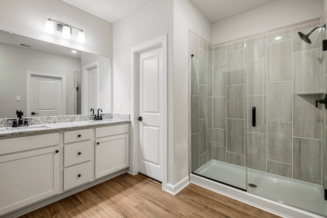15683 Honey Cove Dr, Conroe, TX 77303 - bathroom featuring a stall shower, double vanity, wood finished floors, and baseboards