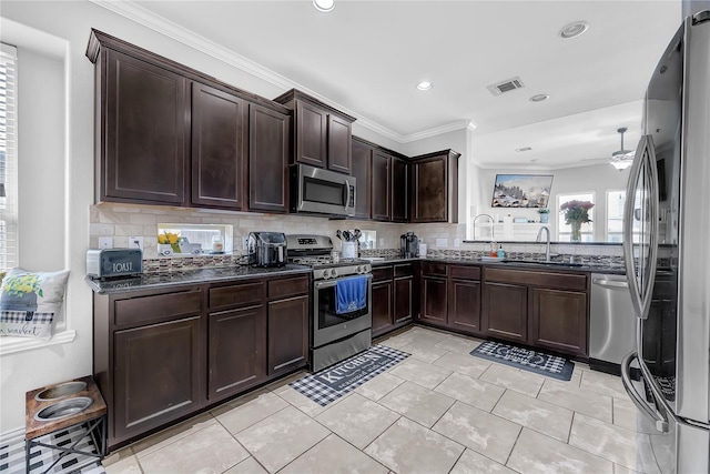 21275 Lily Springs Dr, Porter, TX 77365 - kitchen featuring appliances with stainless steel finishes, backsplash, dark stone countertops, dark brown cabinetry, and ornamental molding