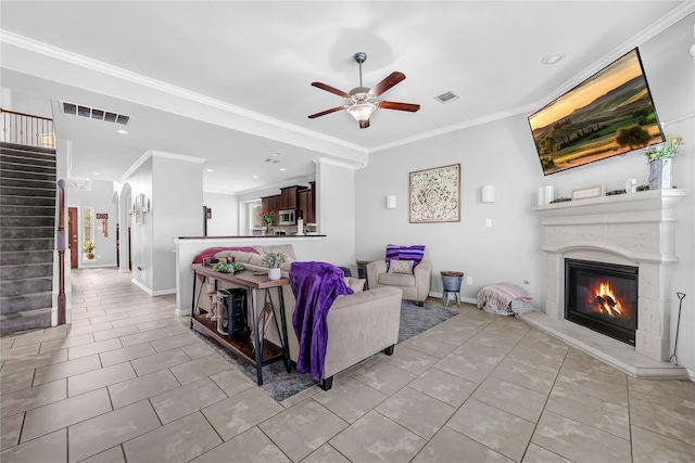 21275 Lily Springs Dr, Porter, TX 77365 - living room with a ceiling fan, stairs, light tile patterned flooring, a glass covered fireplace, and ornamental molding