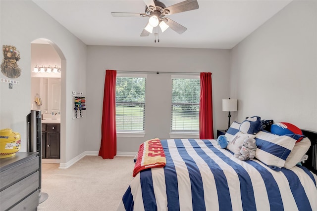 27326 S Karaugh Dr, Richmond, TX 77406 - bedroom featuring light colored carpet, arched walkways, baseboards, ensuite bath, and ceiling fan