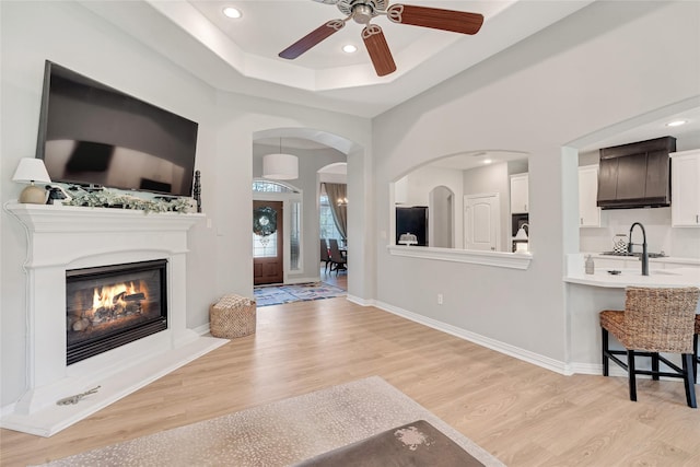 27326 S Karaugh Dr, Richmond, TX 77406 - unfurnished living room featuring light wood-style flooring, ceiling fan, recessed lighting, a glass covered fireplace, and arched walkways