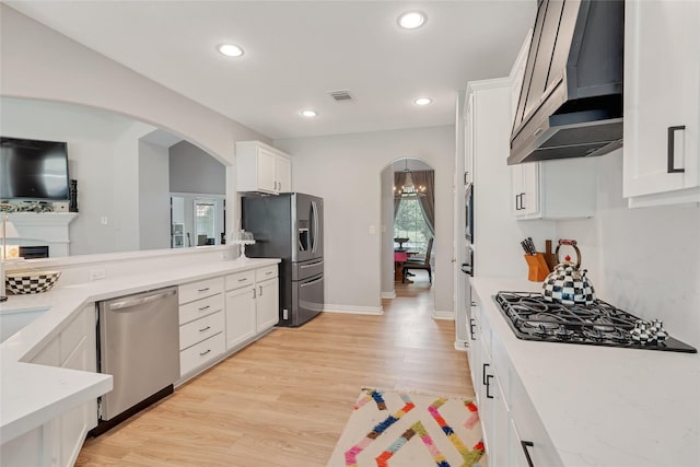 27326 S Karaugh Dr, Richmond, TX 77406 - kitchen featuring stainless steel appliances, wall chimney range hood, arched walkways, light countertops, and white cabinets