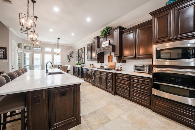 9811 Orchid Cove Ct, Cypress, TX 77433 - kitchen with appliances with stainless steel finishes, a sink, a breakfast bar, ornamental molding, and a chandelier