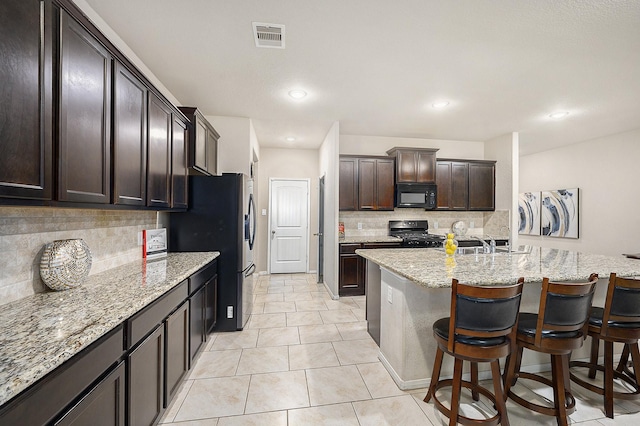 9407 Mineral Rock Ln, Richmond, TX 77407 - kitchen featuring black microwave, gas range oven, tasteful backsplash, stainless steel fridge, and light stone counters