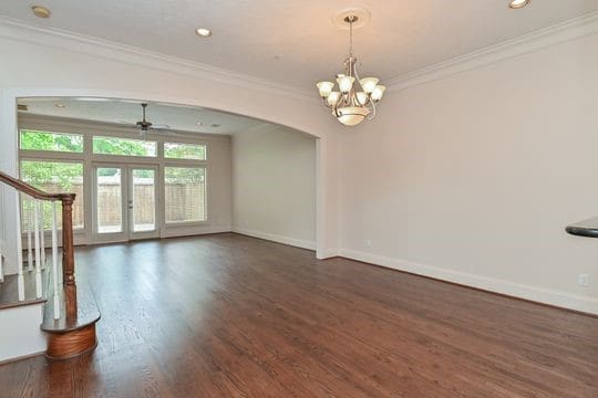 5422 Gibson St Unit A, Houston, TX 77007 - unfurnished living room with arched walkways, crown molding, baseboards, wood finished floors, and a chandelier
