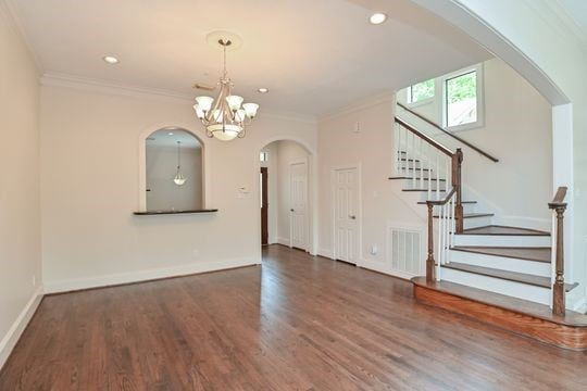 5422 Gibson St Unit A, Houston, TX 77007 - unfurnished living room with a chandelier, stairway, wood finished floors, ornamental molding, and arched walkways
