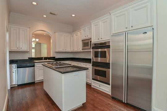 5422 Gibson St Unit A, Houston, TX 77007 - kitchen with built in appliances, dark countertops, arched walkways, a kitchen island, and crown molding