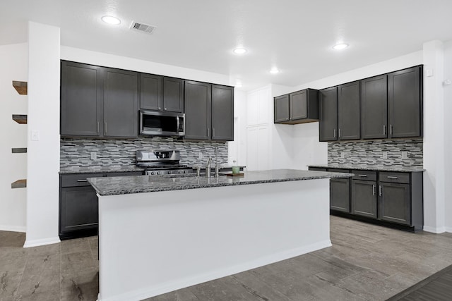14806 Meadow Acre Trl, Houston, TX 77049 - kitchen with appliances with stainless steel finishes, a sink, dark stone counters, backsplash, and a kitchen island with sink