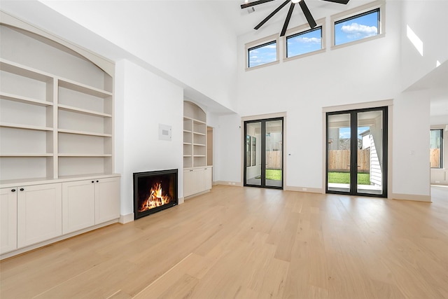 1253 Lamonte Ln, Houston, TX 77018 - unfurnished living room with a warm lit fireplace, a towering ceiling, built in shelves, light wood finished floors, and baseboards