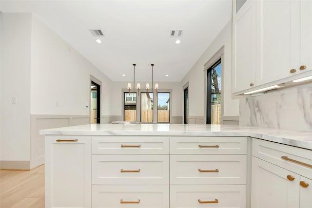 1253 Lamonte Ln, Houston, TX 77018 - kitchen featuring a peninsula, light stone countertops, white cabinets, light wood finished floors, and backsplash