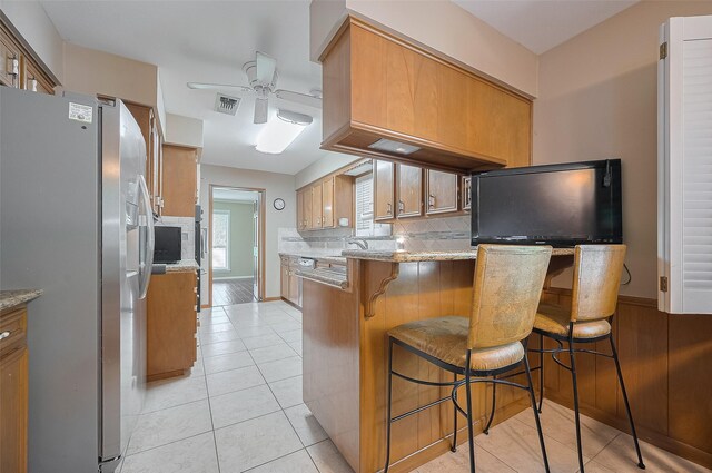 1214 Lindsey Dr, Rosenberg, TX 77471 - kitchen with stainless steel fridge with ice dispenser, backsplash, a peninsula, ceiling fan, and brown cabinetry