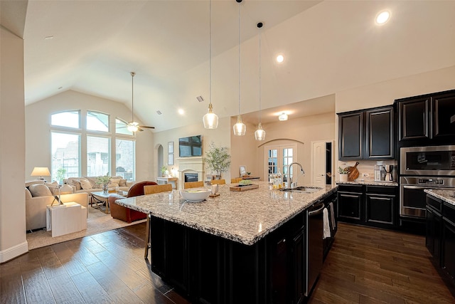 2625 Blooming Field Ln, Conroe, TX 77385 - kitchen featuring appliances with stainless steel finishes, a sink, arched walkways, dark cabinets, and high vaulted ceiling