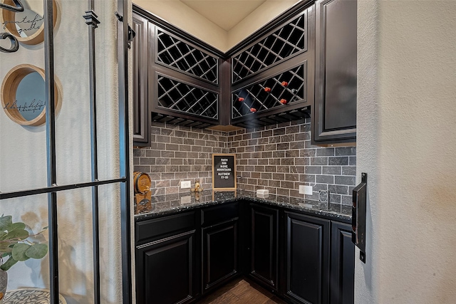 2625 Blooming Field Ln, Conroe, TX 77385 - kitchen featuring backsplash, dark stone counters, dark wood-style floors, and dark cabinetry