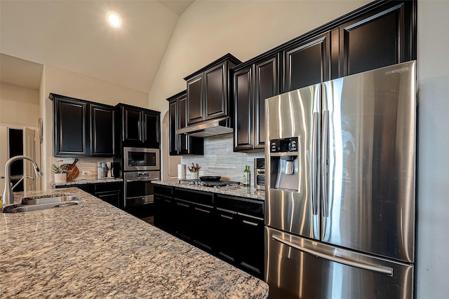 2625 Blooming Field Ln, Conroe, TX 77385 - kitchen with appliances with stainless steel finishes, a sink, dark cabinets, vaulted ceiling, and backsplash