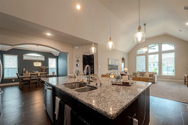 2625 Blooming Field Ln, Conroe, TX 77385 - kitchen featuring a sink, arched walkways, dark wood finished floors, lofted ceiling, and a center island with sink