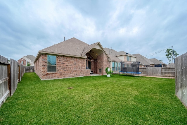 2625 Blooming Field Ln, Conroe, TX 77385 - back of house with a trampoline, brick siding, and roof with shingles